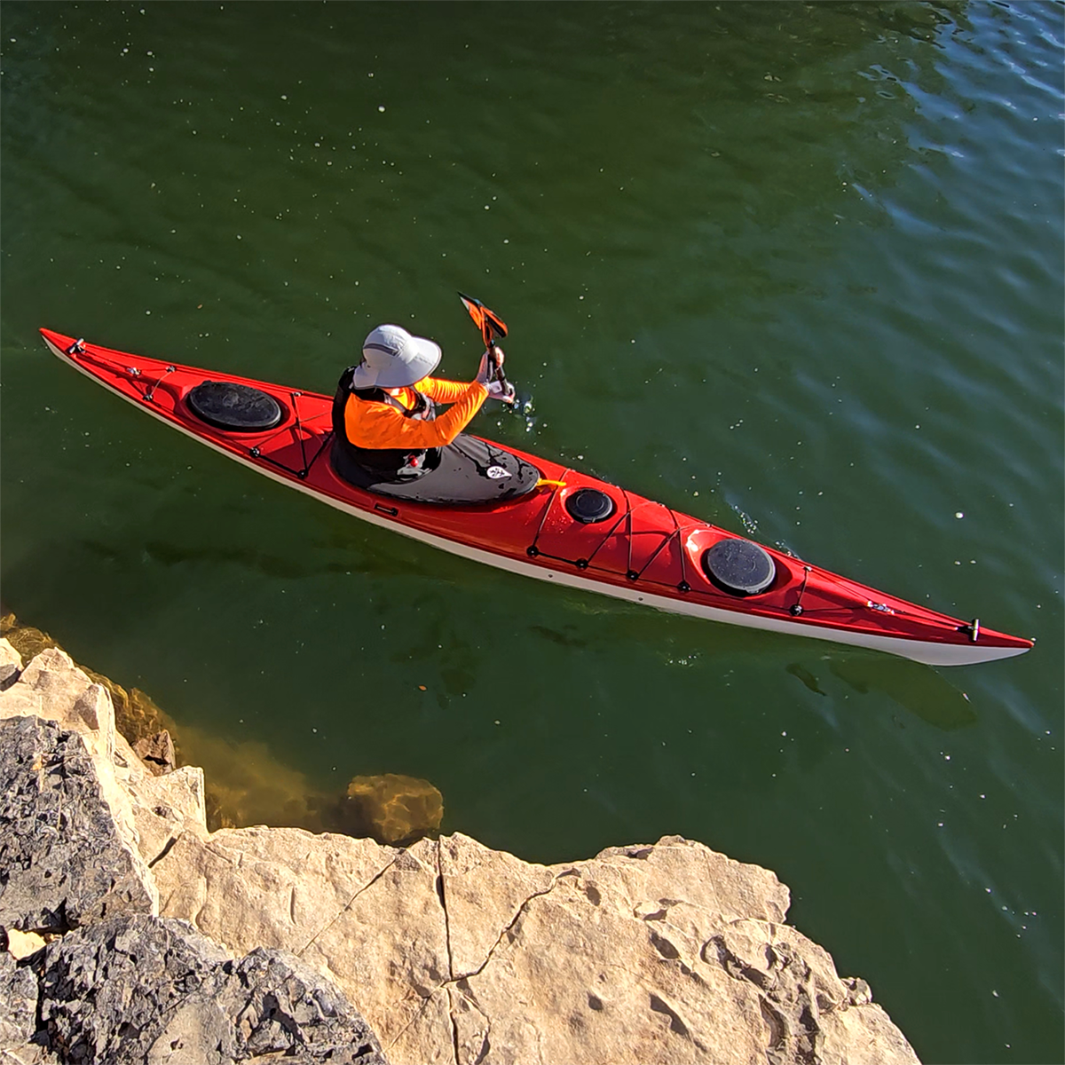 Kayaker on water wearing Paragon Cayman Hi-Visibility Sun Shirt Neon Orange